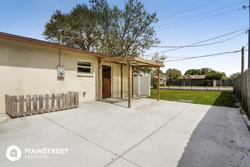 a small white house with a driveway and a white fence