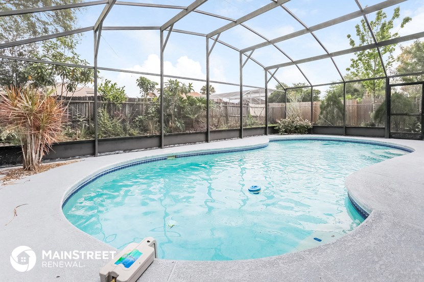 a resort style pool with a fence around it and a hot tub next to it