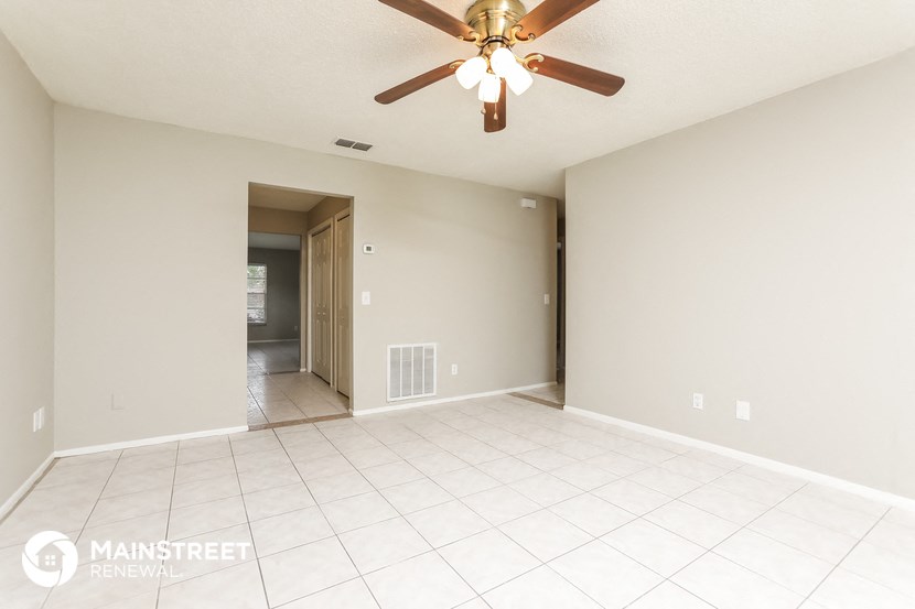 the spacious living room with tile flooring and a ceiling fan