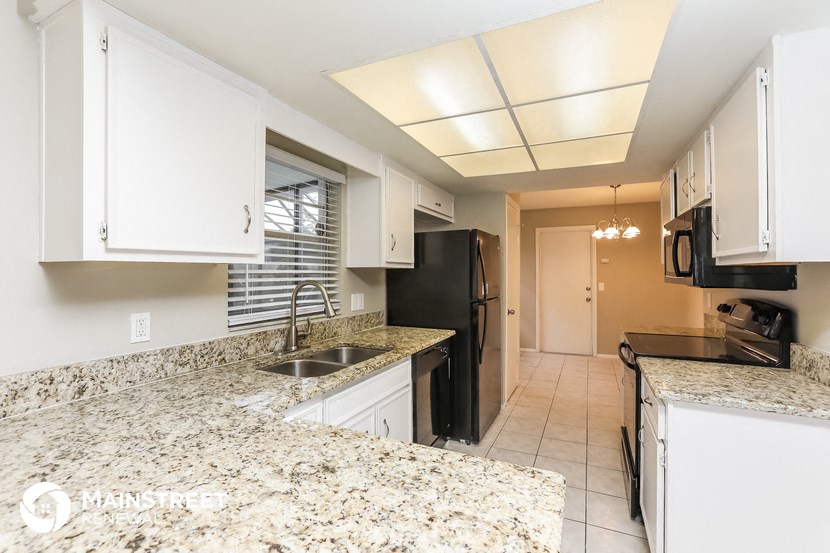 a kitchen with granite counter tops and a black refrigerator