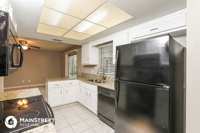 a kitchen with a black refrigerator and white cabinets
