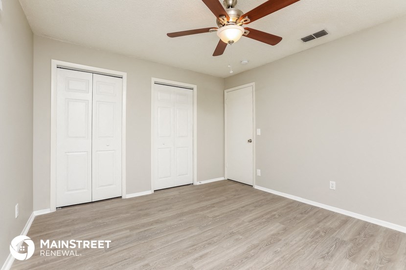 the spacious living room with 2 closets and a ceiling fan