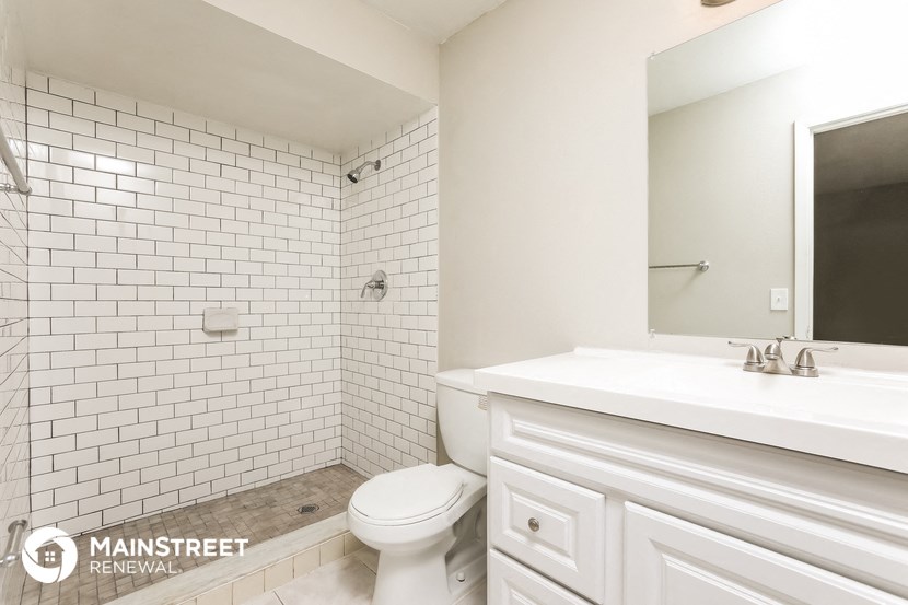 a white tiled bathroom with a toilet and a sink