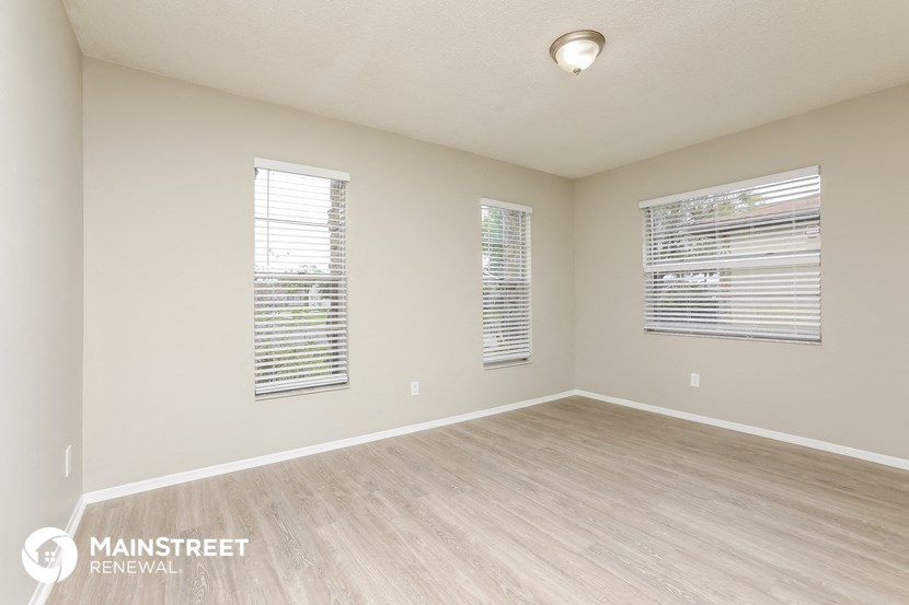 the spacious living room with wood flooring and windows