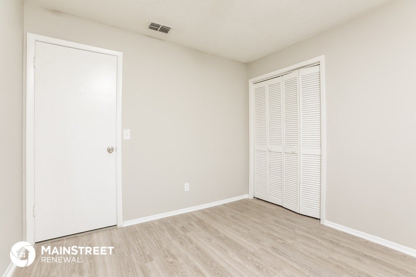 the spacious living room with white walls and wood flooring