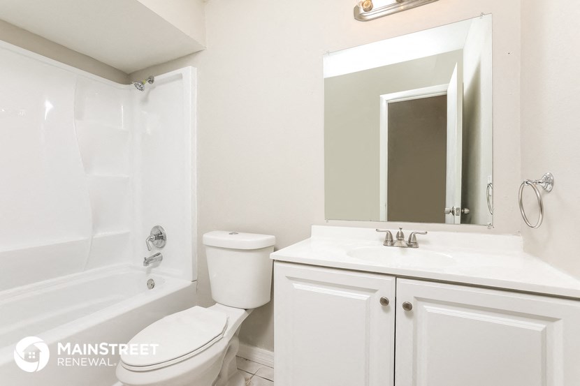 a white bathroom with a toilet sink and tub and a mirror