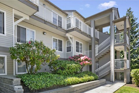 A grey apartment building with a staircase leading to the second floor.