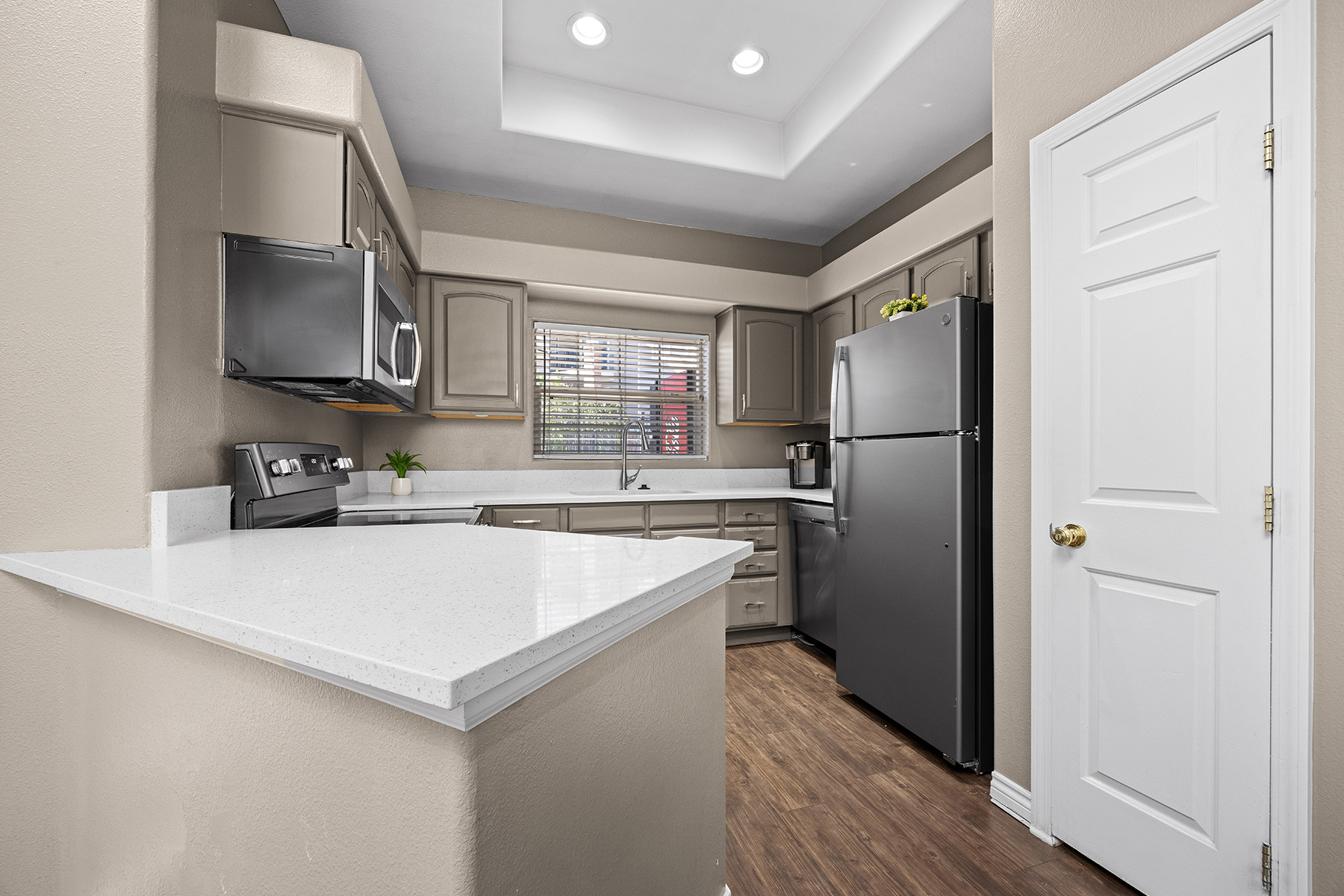 A kitchen with a white countertop and a black refrigerator.