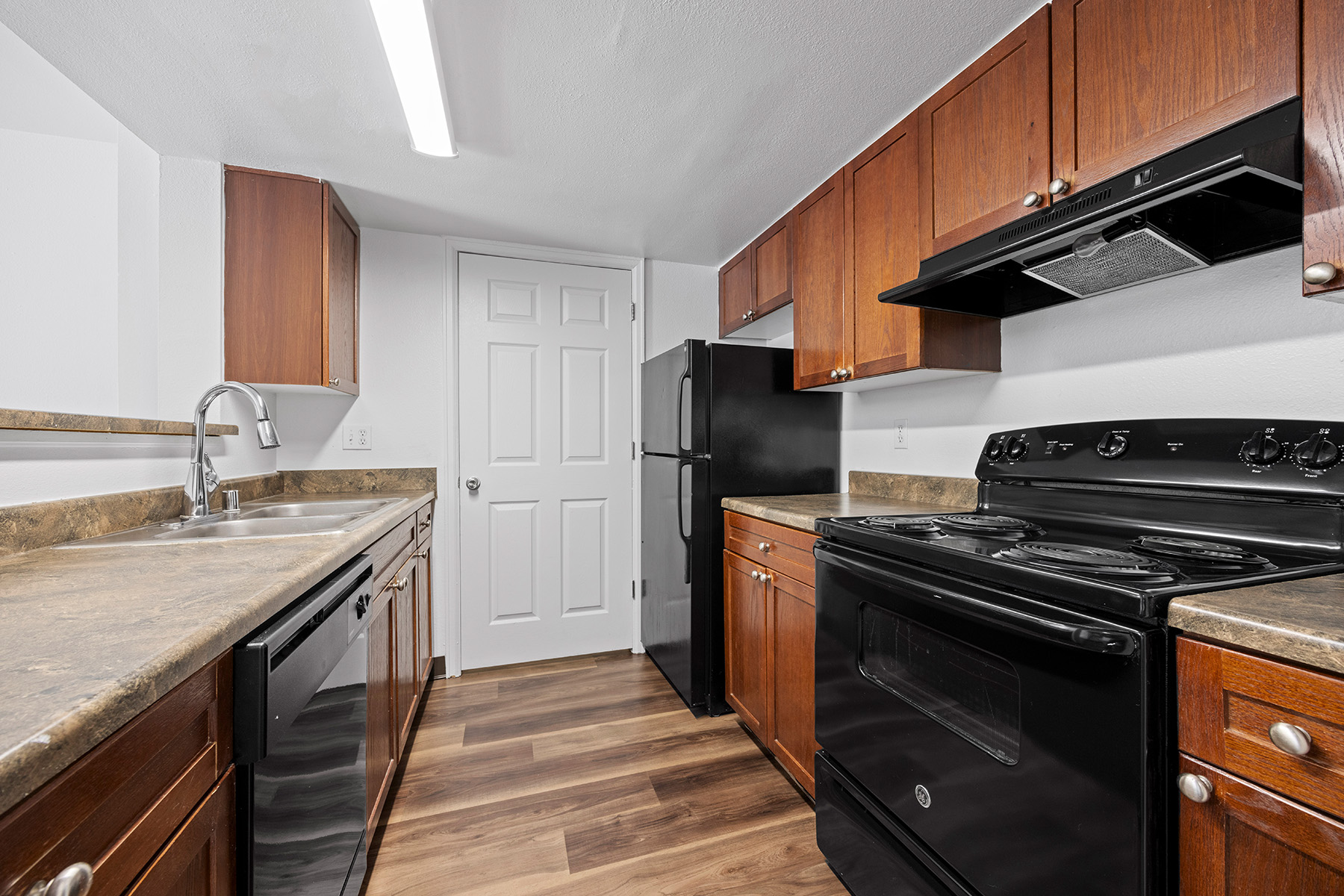 A kitchen with black appliances and wooden cabinets.