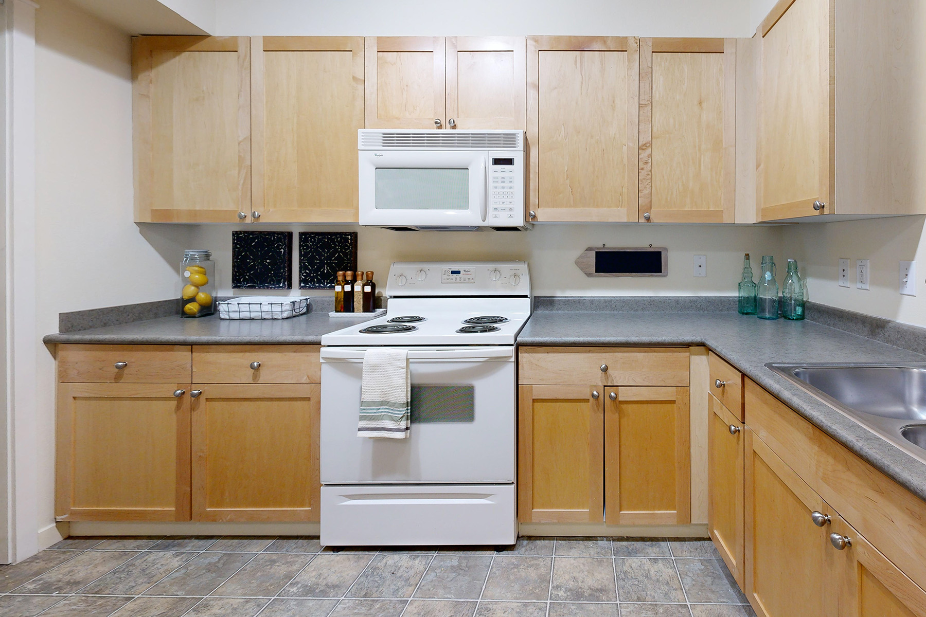 A kitchen with wooden cabinets and a white stove top oven.