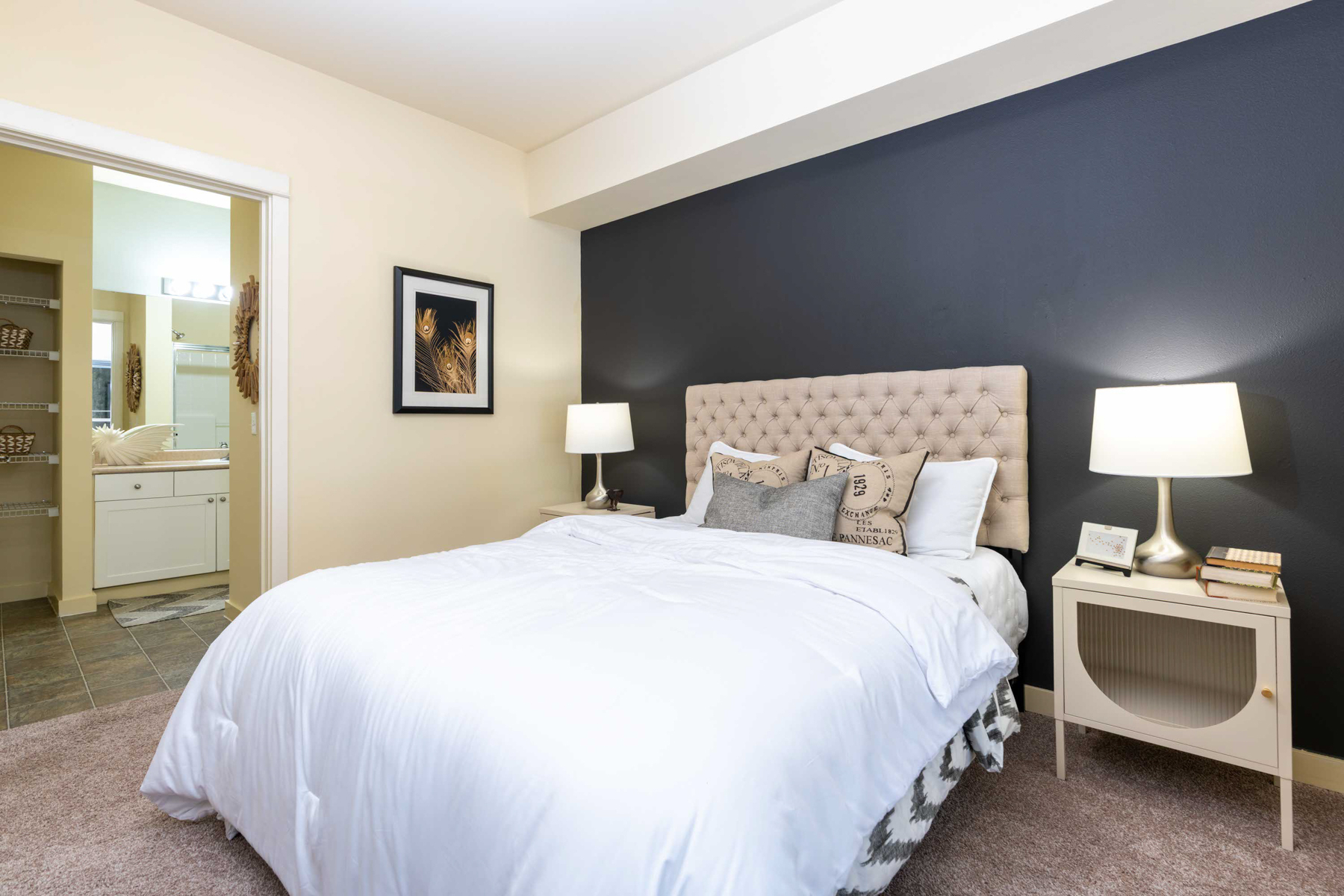 A bedroom with a white bed and a picture on the wall.
