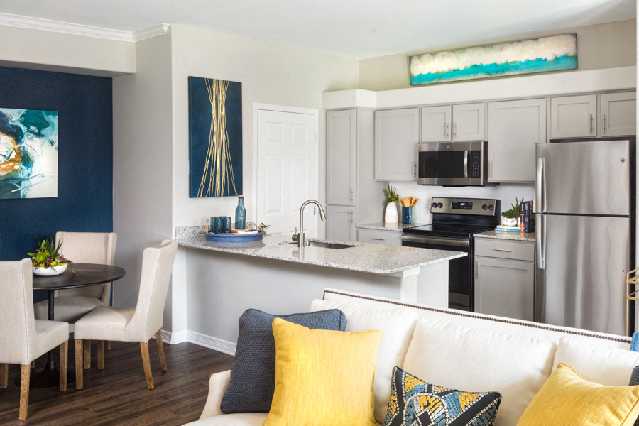 a living room with a couch and a kitchen with stainless steel appliances