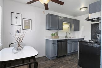 a kitchen with gray cabinets and a white table and a black refrigerator