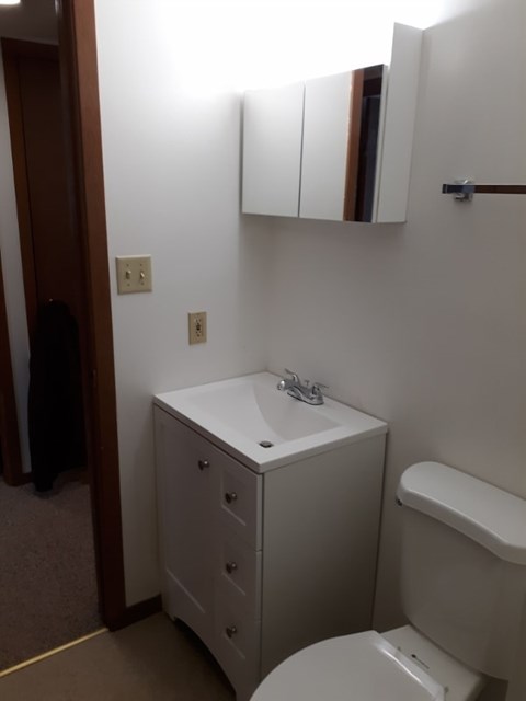 A white bathroom with a toilet, sink, and medicine cabinet.