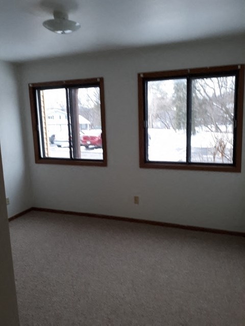A room with two windows and carpeted floor.