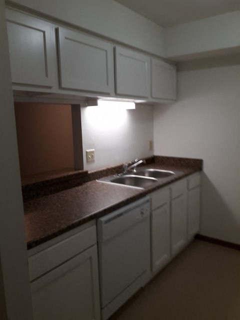 A kitchen with brown countertops and white cabinets.
