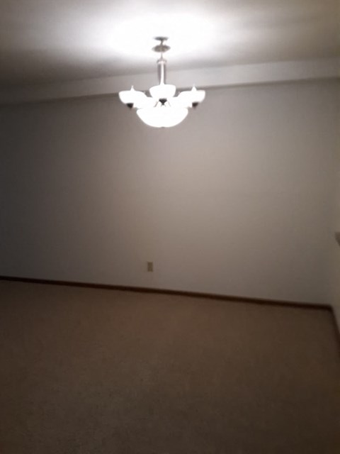 A chandelier hangs from the ceiling in a room with a carpeted floor.