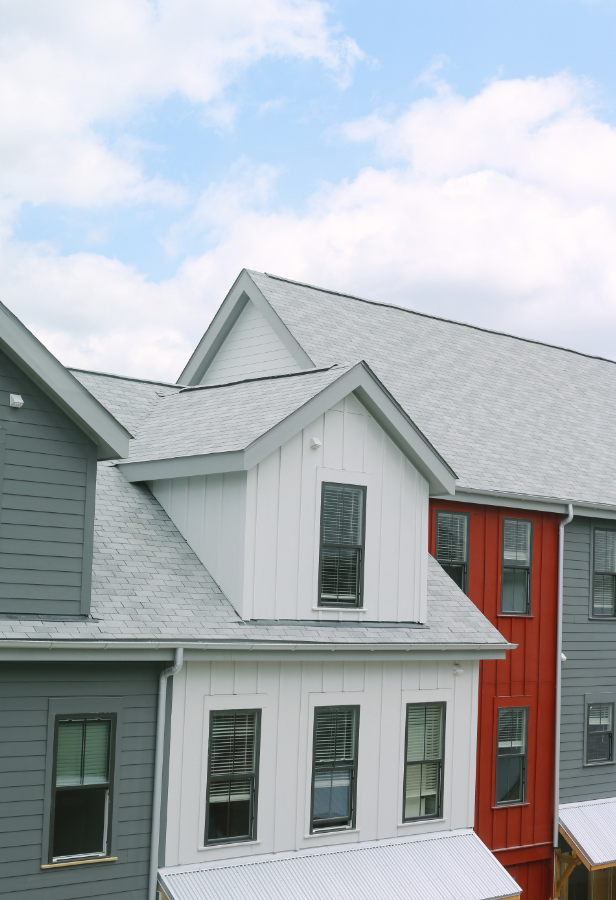 a white house with a gray roof and a red house