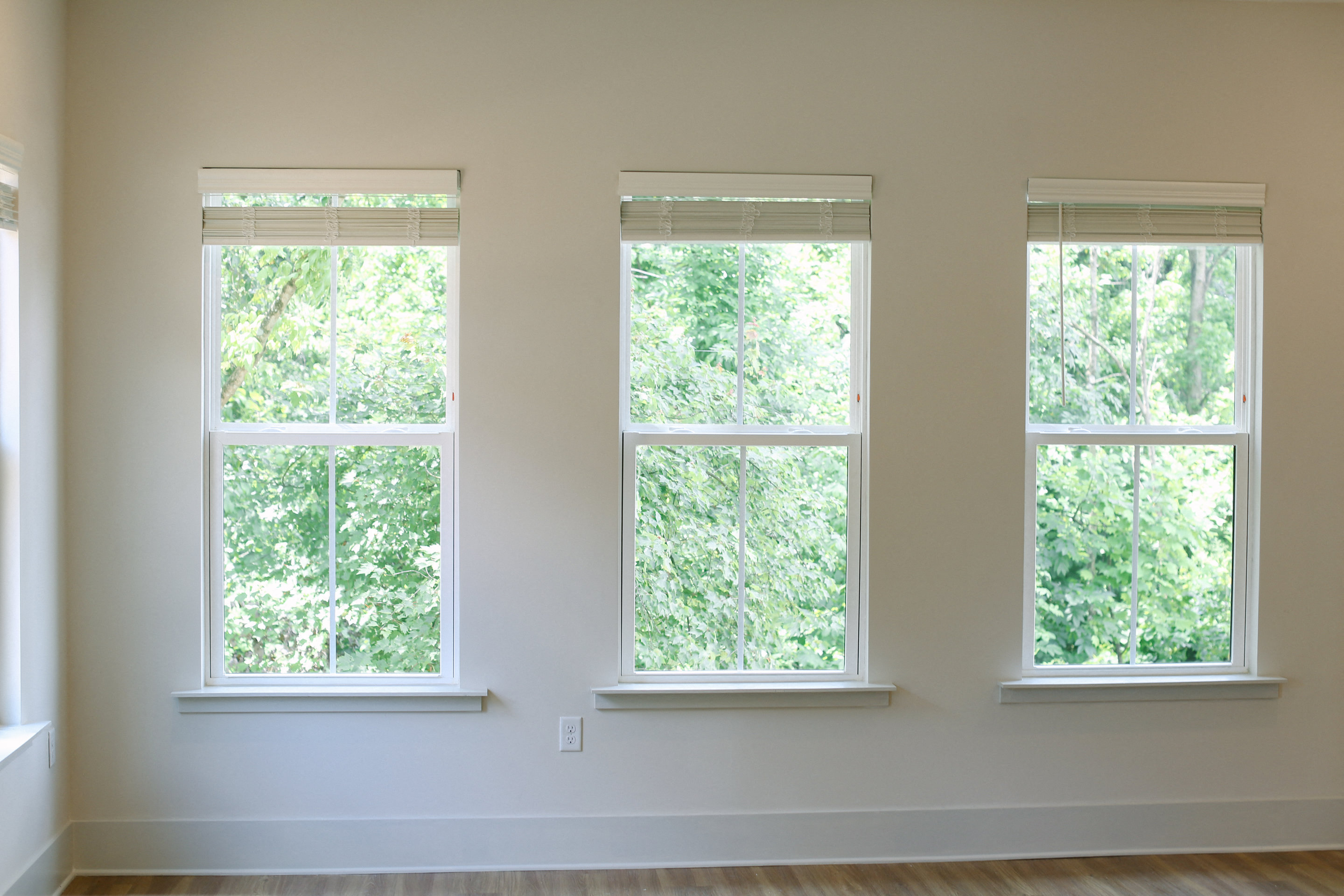 three windows in an empty living room with a wood floor
