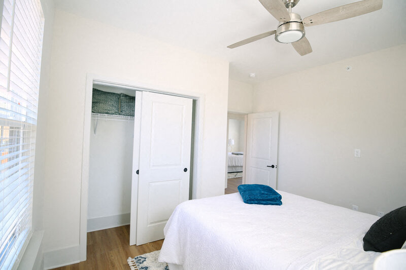 a bedroom with a white bed and a ceiling fan