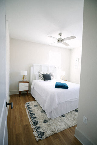 a bedroom with a white bed and a ceiling fan