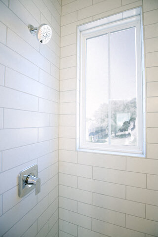 a white tiled shower with a window in it