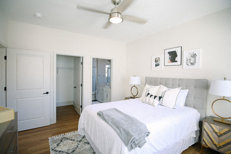 a bedroom with a white bed and a ceiling fan