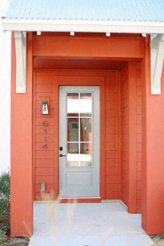 a red building with a blue door with a window