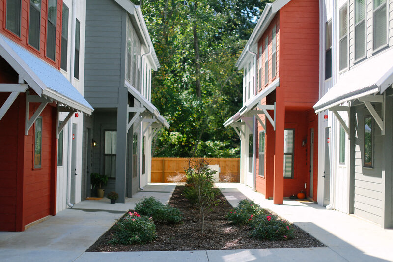 a walkway between two houses with trees in the background