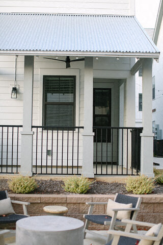 a patio with chairs and tables in front of a house