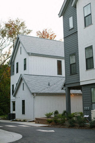 a white house and a gray house next to a street
