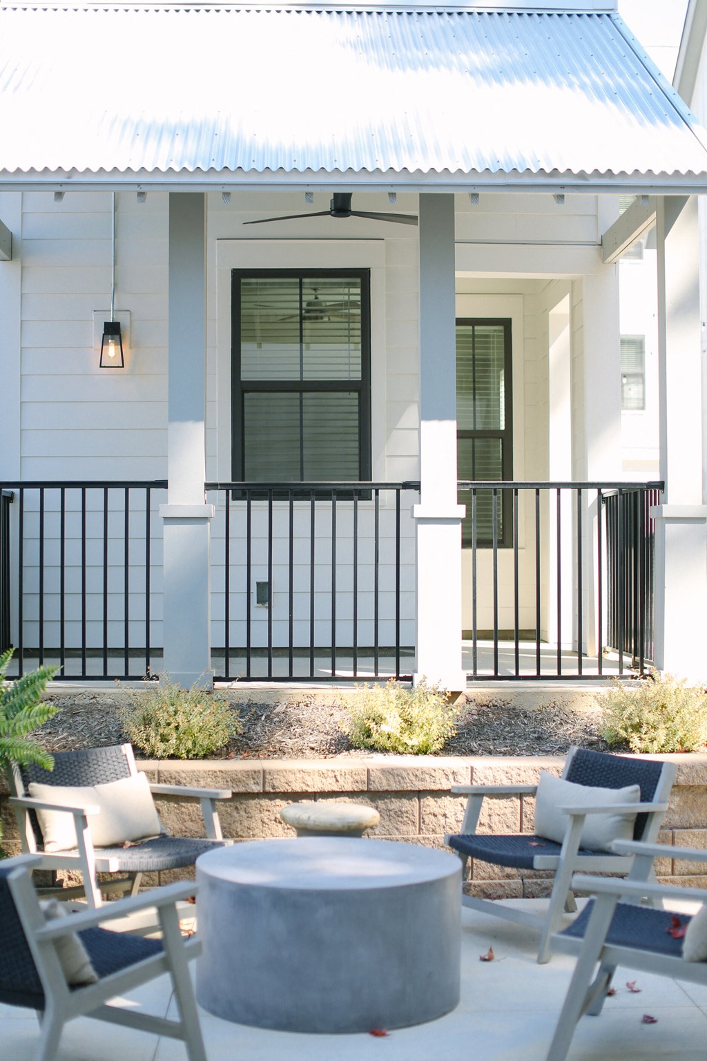 a patio with chairs and tables in front of a house