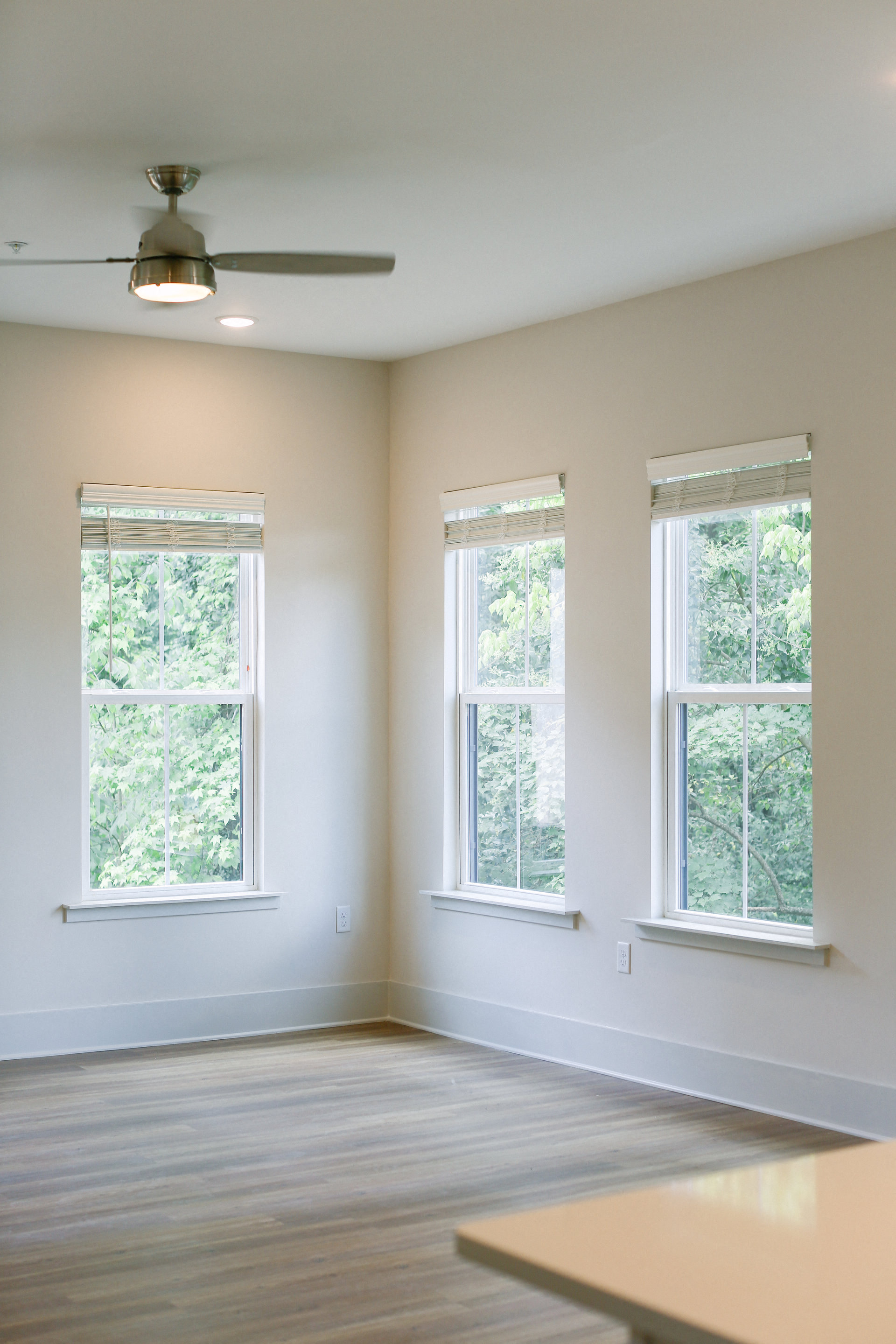 an empty room with a wood floor and three windows