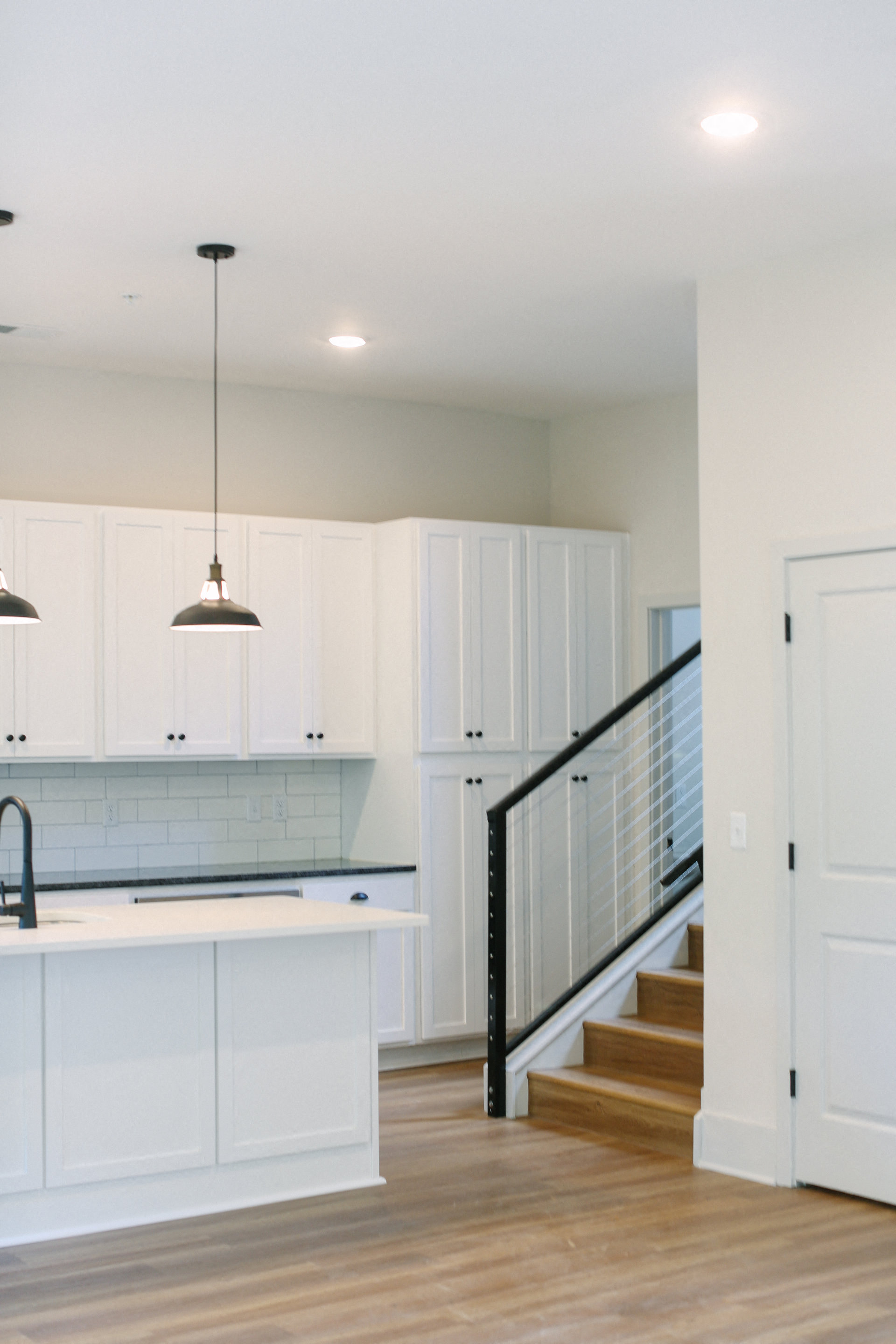 a white kitchen with white cabinets and a staircase