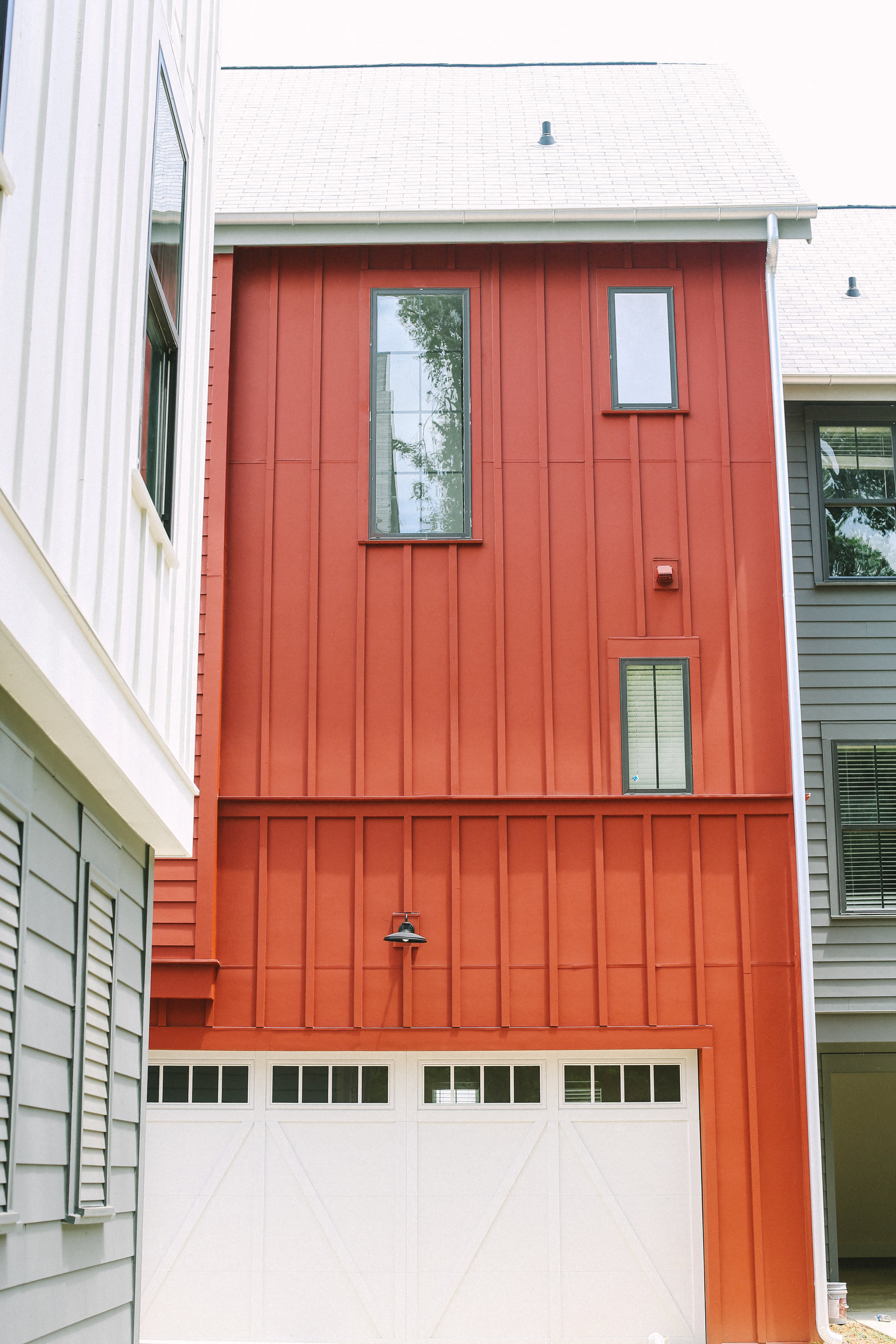 the side of a red house with a garage door