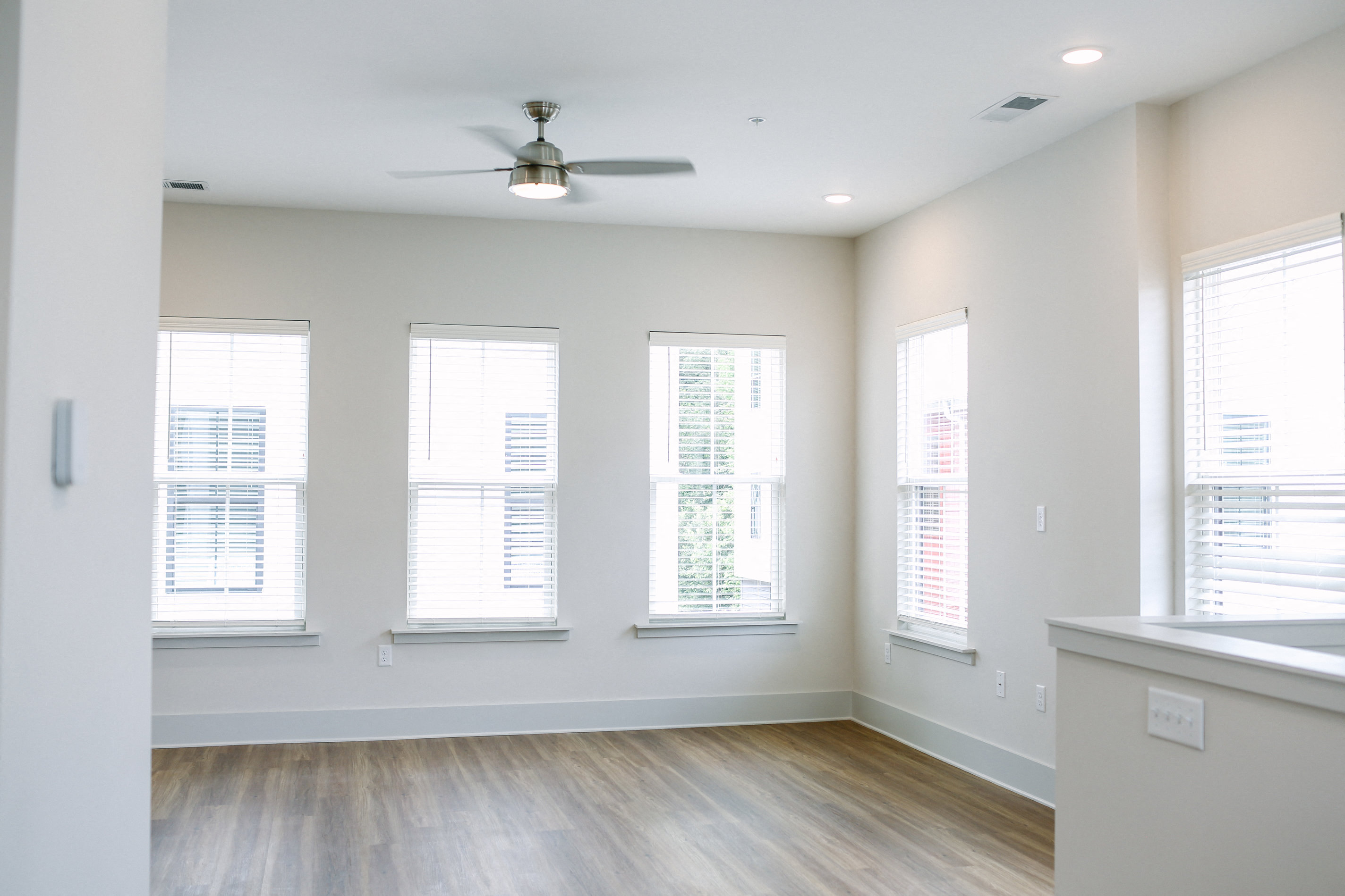 an empty living room with windows and a ceiling fan