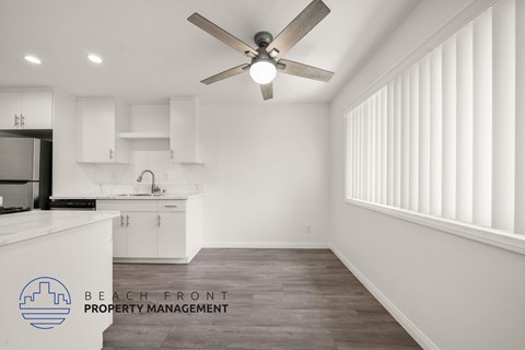 A spacious kitchen and living room with a ceiling fan and wooden flooring.