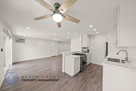 A modern kitchen with a wooden ceiling fan and white cabinets.
