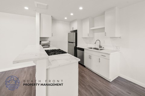 A modern kitchen with white cabinets and a wooden floor.