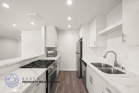 A modern kitchen with white cabinets and a marble countertop.