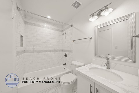A white bathroom with a marble sink and a mirror.