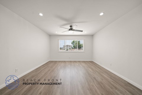 A spacious room with a ceiling fan and wooden flooring.