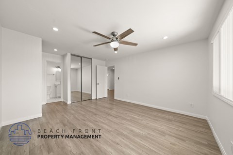 A spacious room with a ceiling fan and wooden flooring.