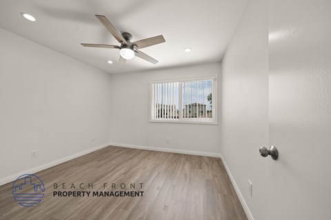 A room with a ceiling fan and wooden flooring.