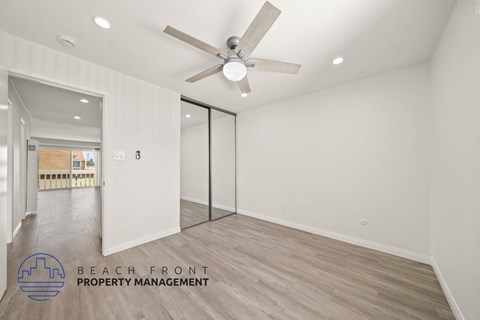 A room with a ceiling fan and a logo for Beach Front Property Management.