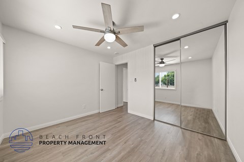 A spacious room with a ceiling fan and a mirror on the wall.