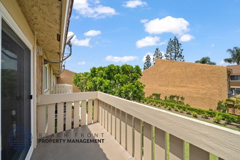A balcony with a view of a building and trees.