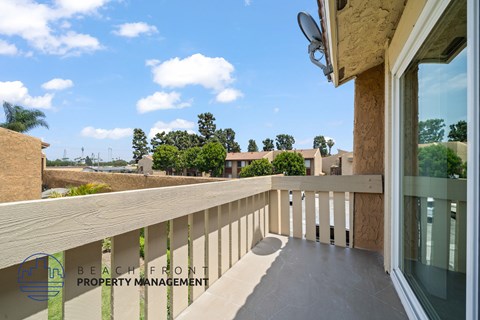 A balcony with a view of the beach and trees.