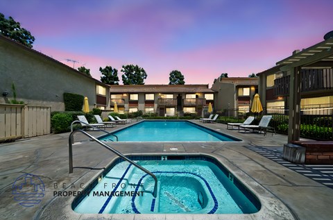 A swimming pool surrounded by lounge chairs and umbrellas.