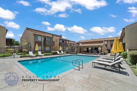 A pool area with lounge chairs and umbrellas is part of a property managed by Beach Front Property Management.